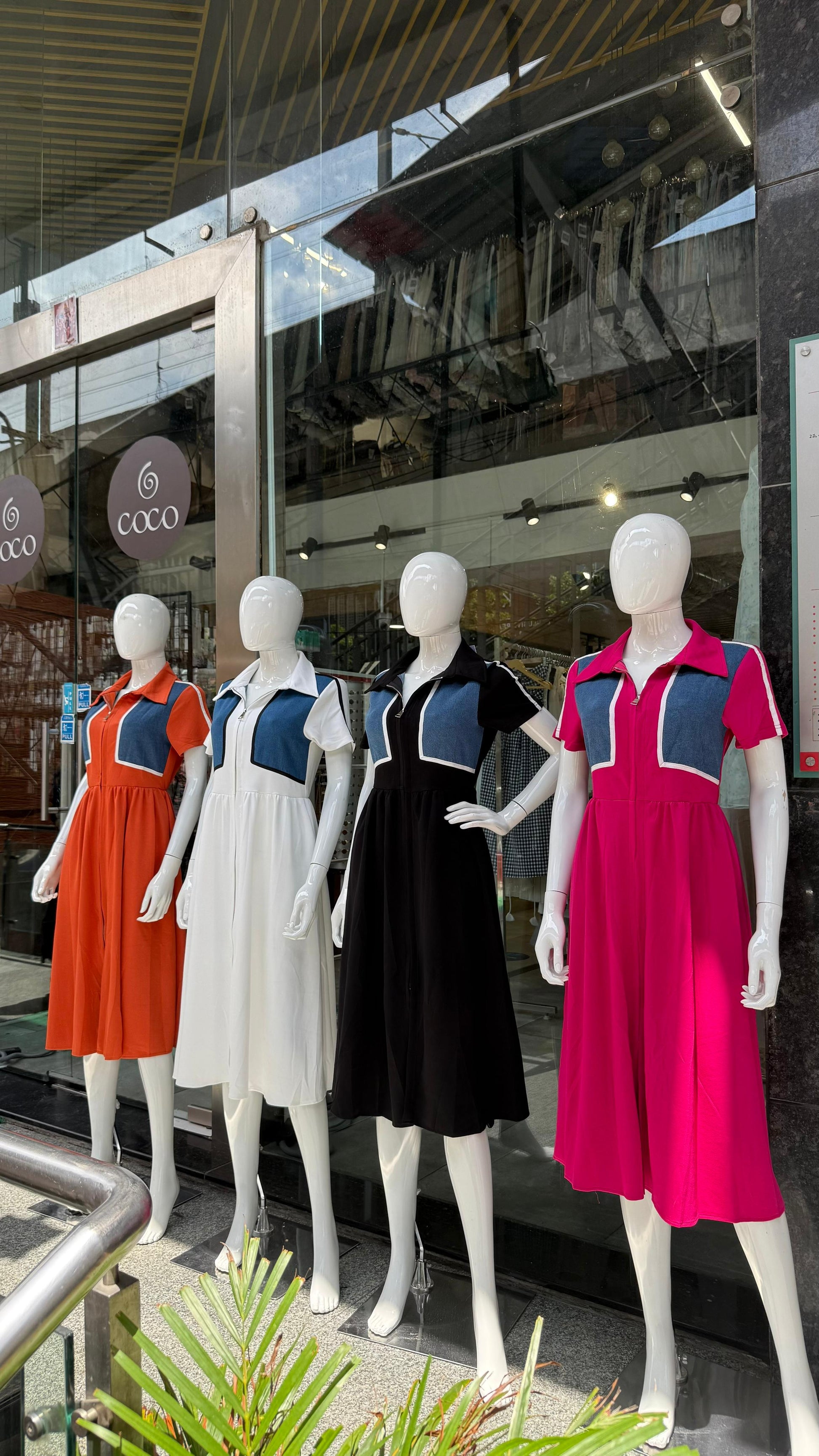 Mannequins wearing colorful dresses in front of a store window.